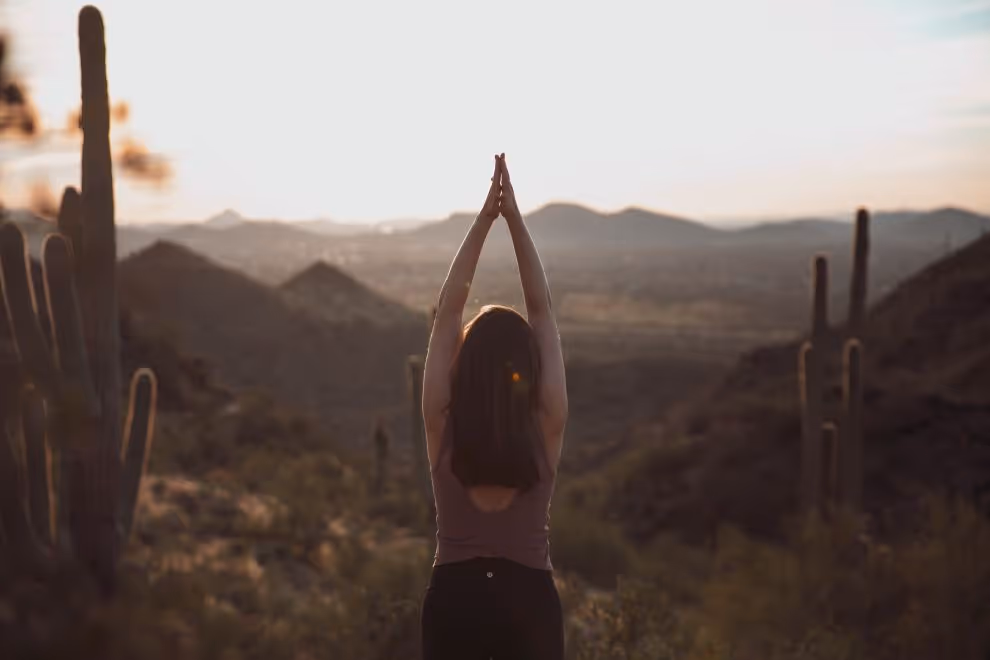 Person doing yoga amid desert landscape with cacti at sunset